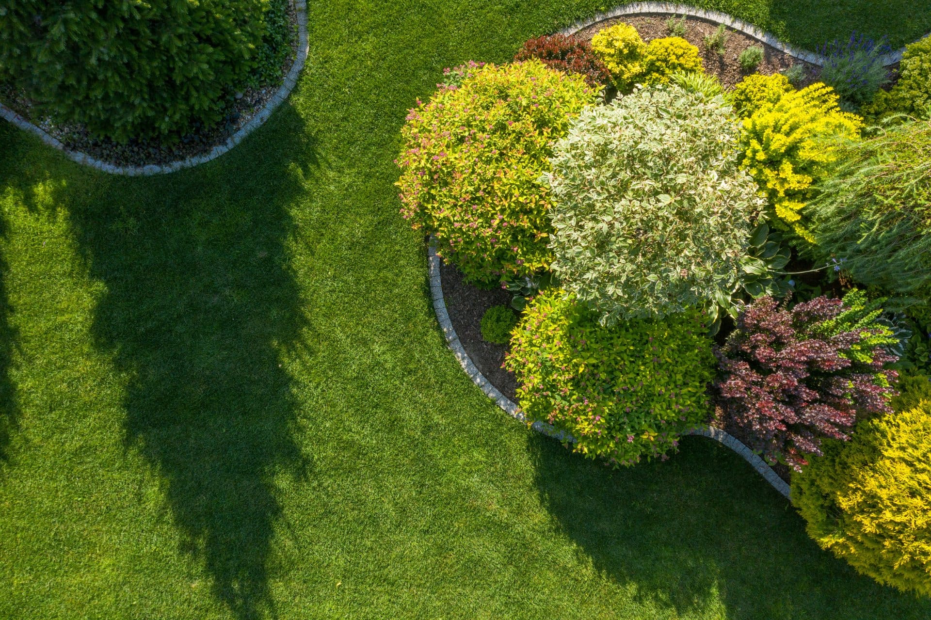 Aerial view of a manicured lawn and curved landscape beds